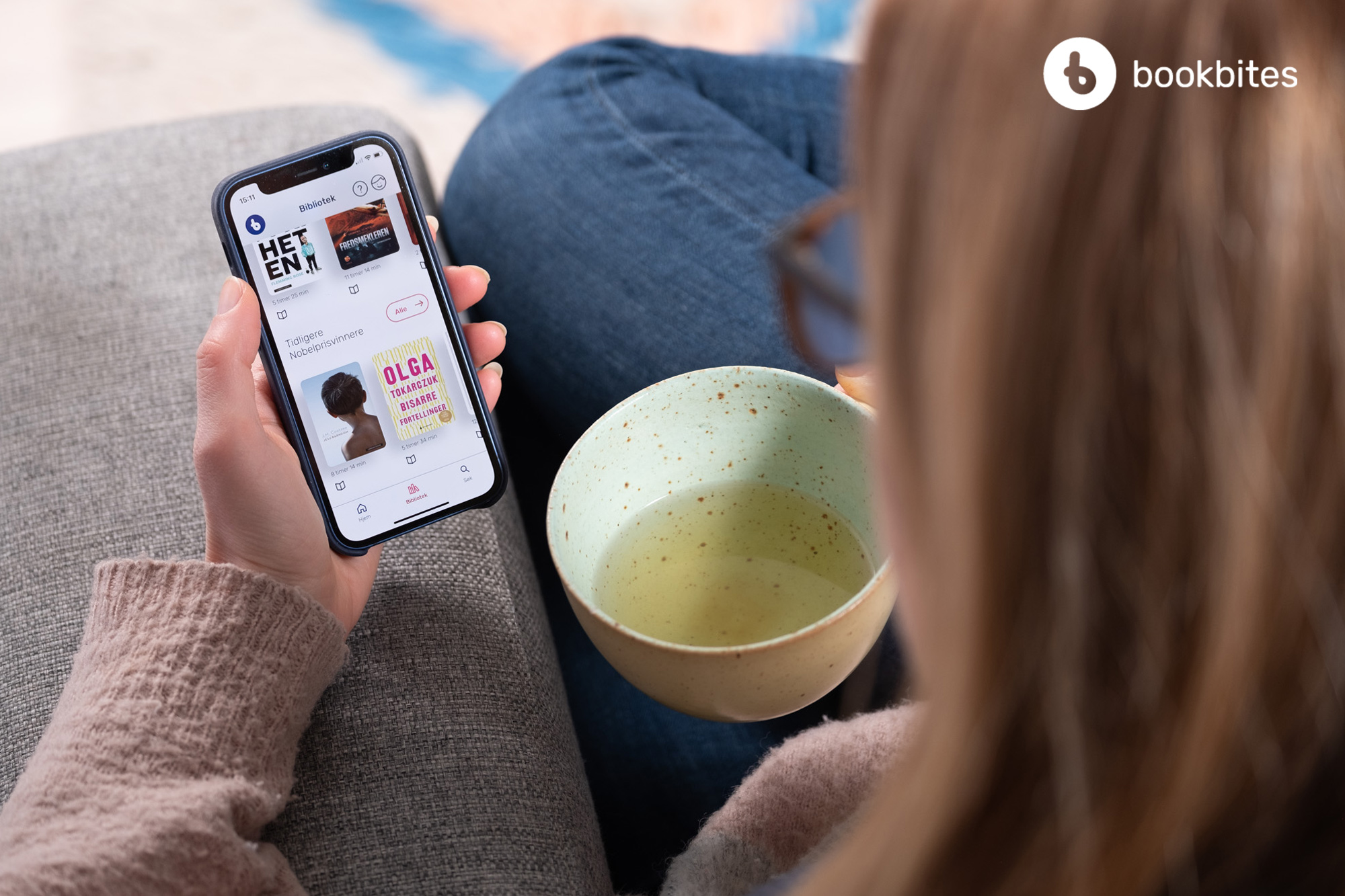 Bilde av ei dame som sitter på digitalt bibliotek på mobilen sin.