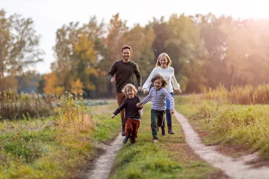 Familie på fire som går og leker på en traktorveg.