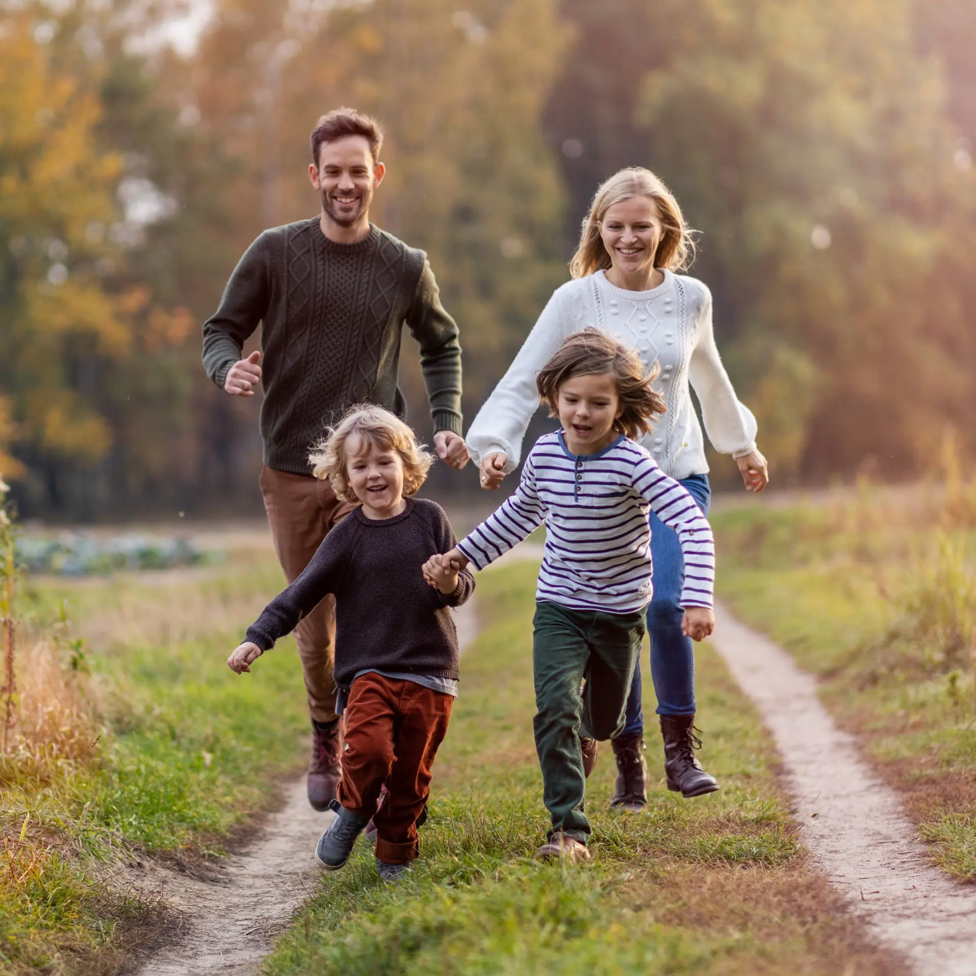 Familie på fire som går tur på en traktorveg.